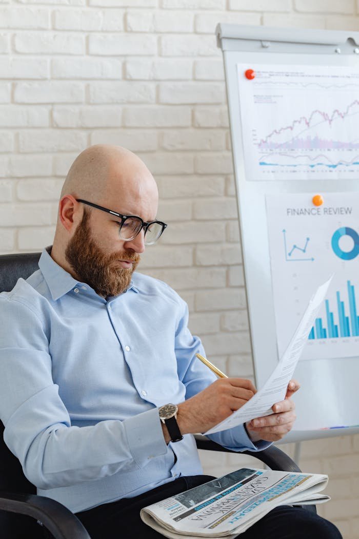 Caucasian businessman reviewing financial documents in a modern office setting.